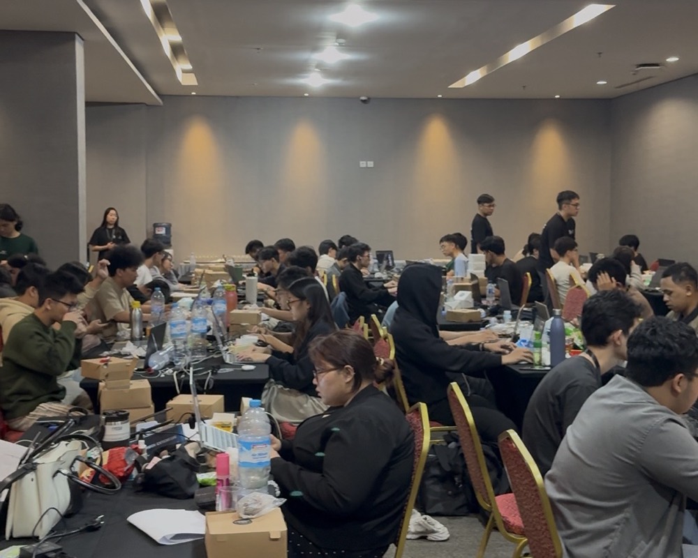 Participants at a packed BNCC Technoscape hackathon, working at long tables of laptops